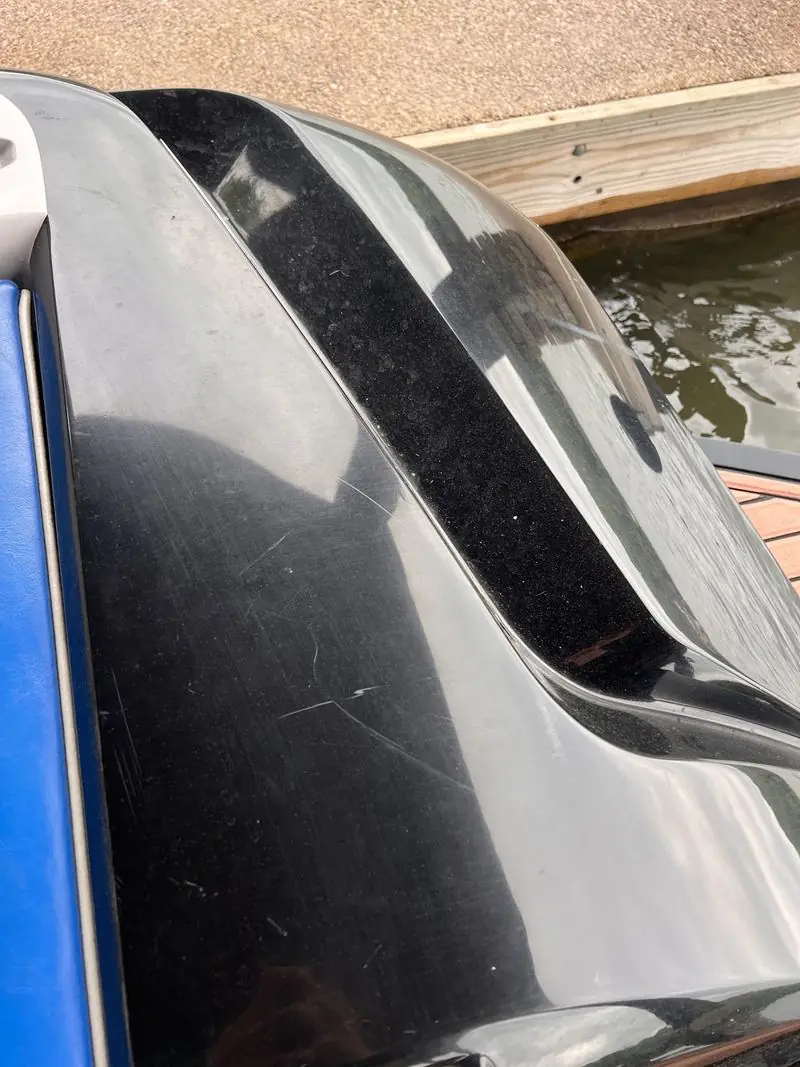 Black hull panel with blue trim before detailing, hazy and scratched
