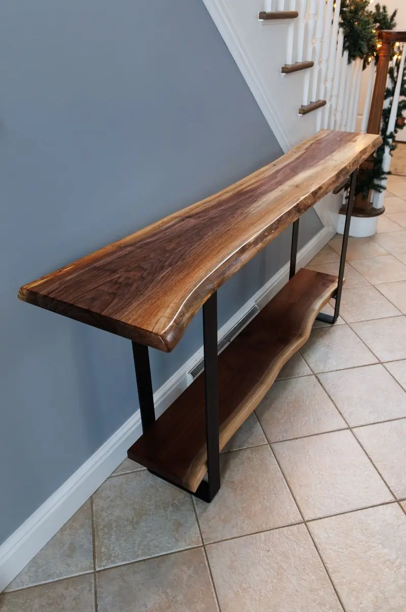 Live-edge wood console table with black steel legs and a lower shelf, in a hallway