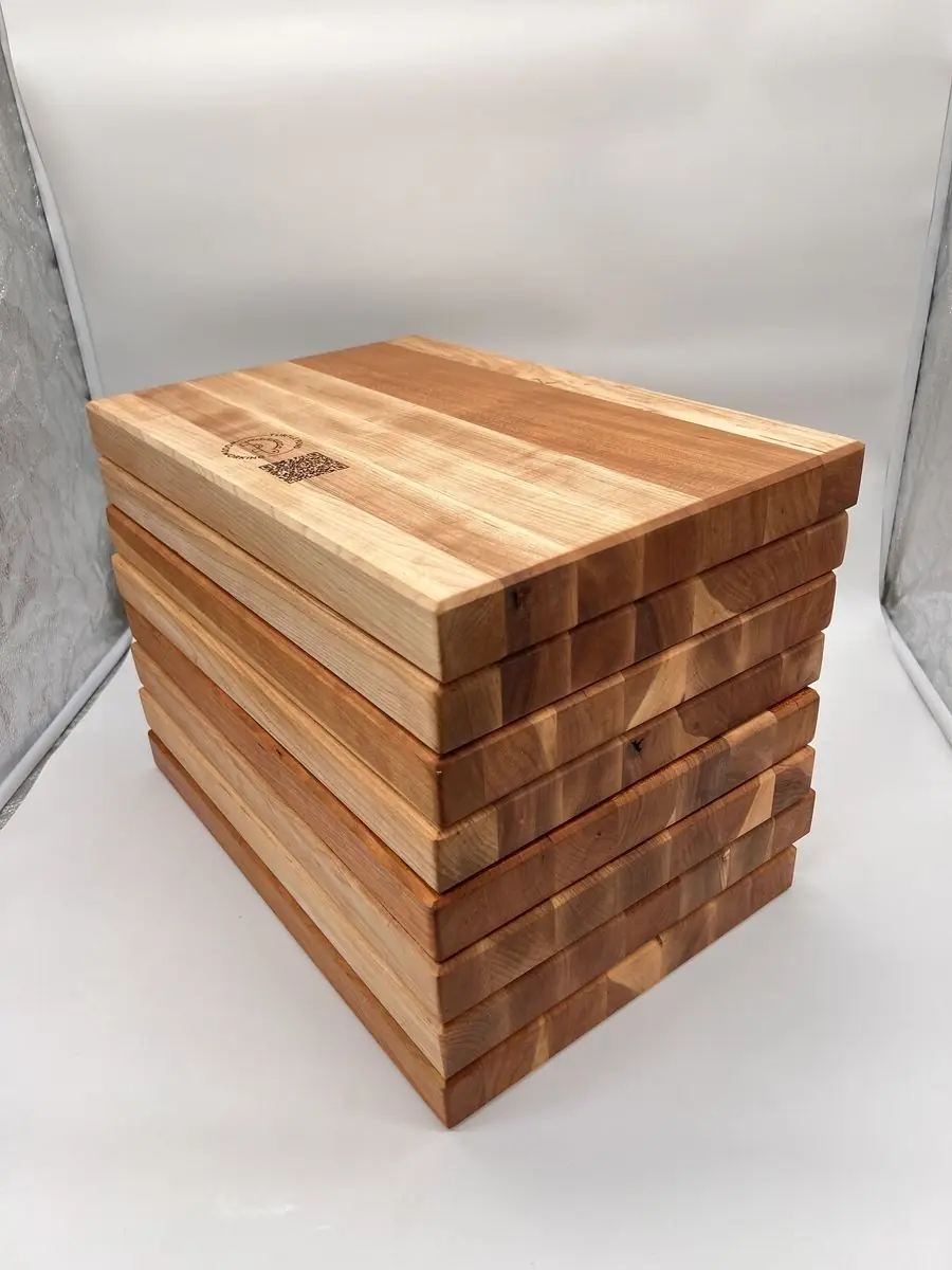 Stack of butcher-block cutting boards; the top one has an engraved Turtle Pond Woodworking logo and QR code